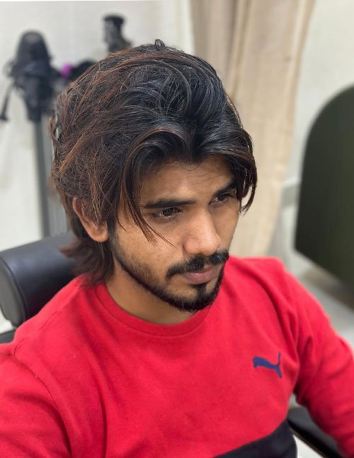 Man with a textured quiff hairstyle, featuring lifted volume at the front, layered length on top, and soft face-framing pieces.