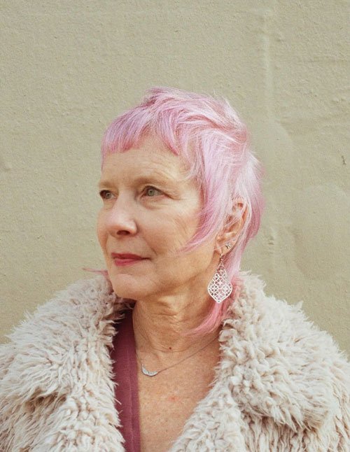 Woman with a textured short shag bob in soft pink tones.