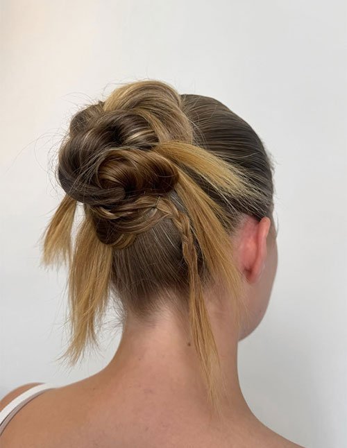 Textured twisted bun with loose pieces and a thin accent braid.