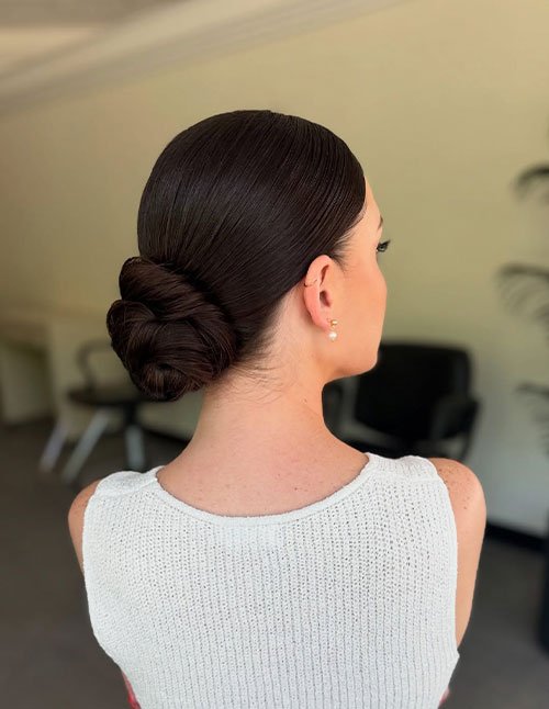 Twist-and-wrap low bun with a sleek middle part and smooth finish, back view.