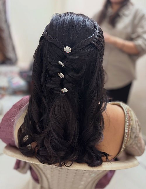 Twisted braid half-up hairstyle on thick wavy hair with small jeweled pins, back view.
