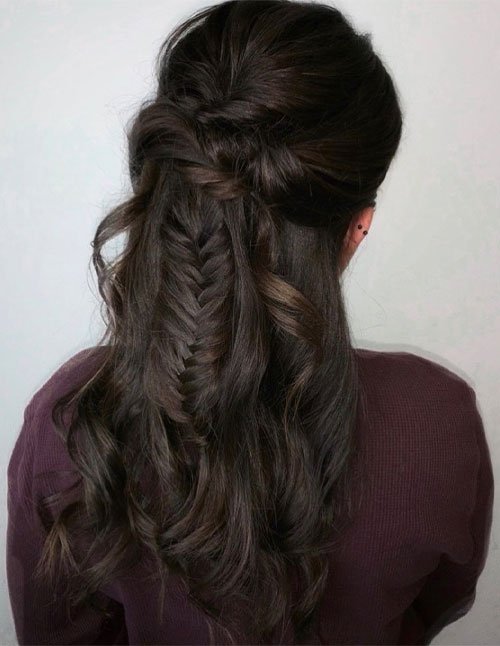Half-up twisted fishtail braid flowing into loose, dark curls down the back.