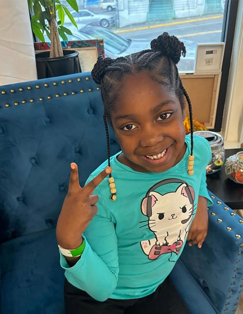 Child wearing twisty mini buns with braided sections and bead accents.