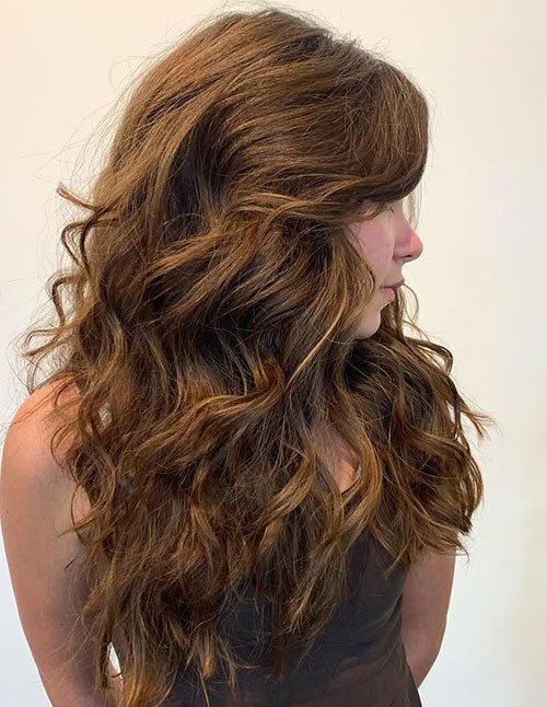 Side view of long hair with voluminous layered curls and soft movement.