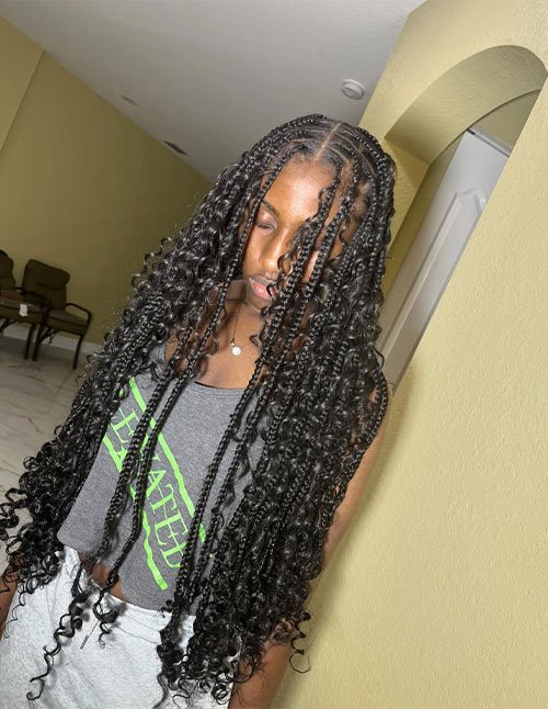 Waist-length braids styled with a neat middle part and clearly defined curly tips for a soft finish.