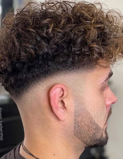 Wavy brush up hairstyle with a voluminous wavy top brushed upward and a clean skin fade on the sides.