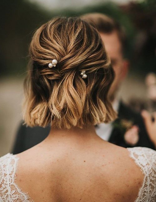 Half-up half-down bridal hairstyle on a short wavy bob with pearl pins.
