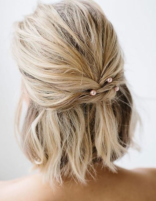 Half-up hairstyle on a short blonde bob with pearl pins.