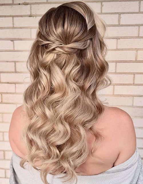 Soft boho rope twist half-up hairstyle on loose blonde waves.